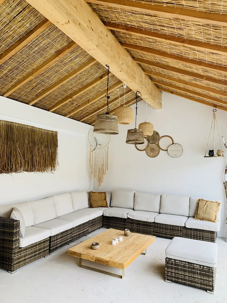 Pool house avec charpente apparente, canisse et salon extérieur